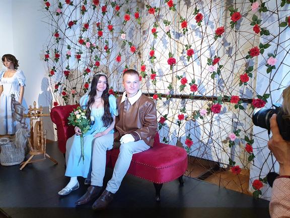 Zwei Jugendliche sind als Dornröschen und Prinz verkleidet und posieren für einen Fotografen auf einem roten Sofa