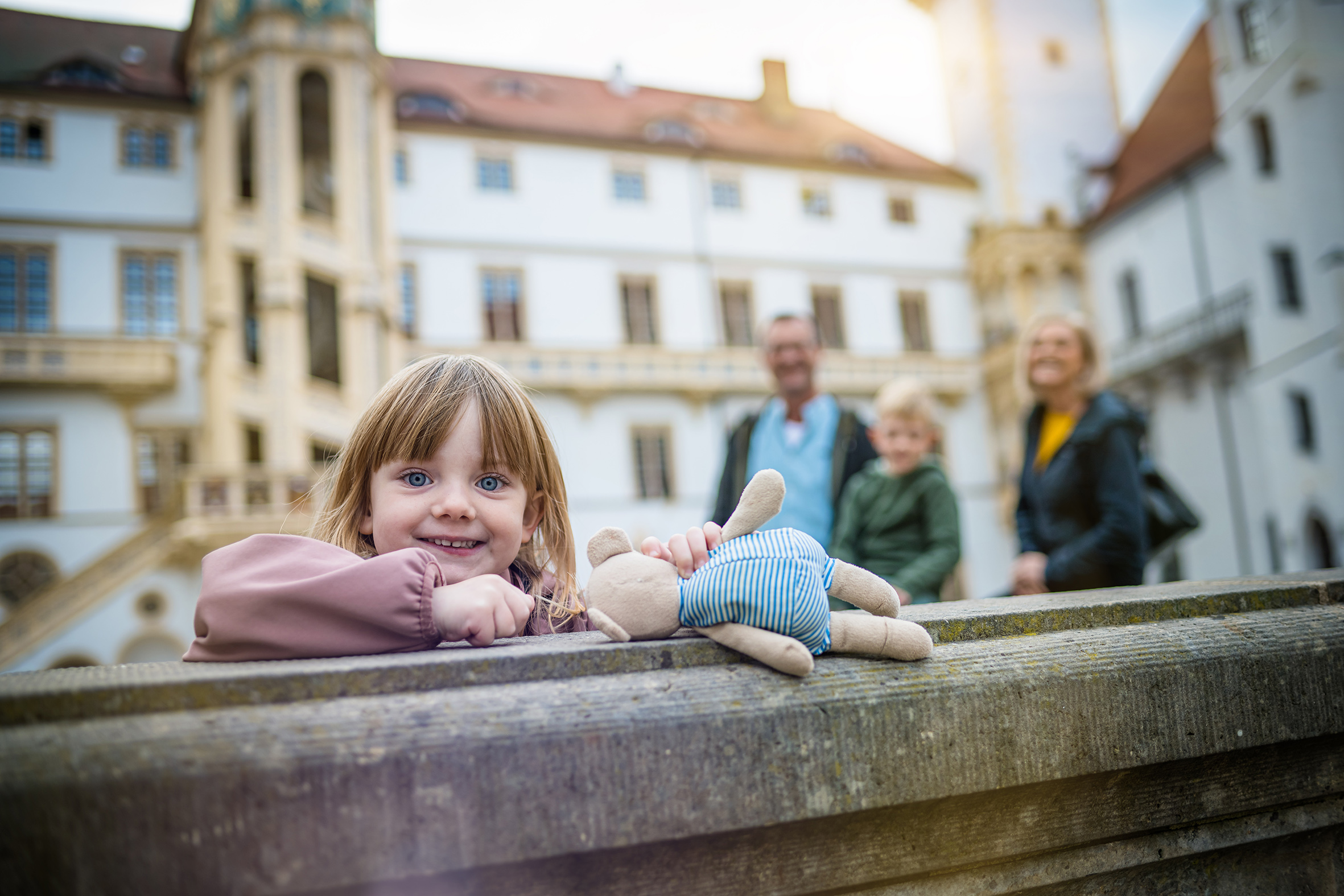 5jähriges Mädchen steht an einem Brunnen und lächelt, dahinter ragt der Große Wendelstein empor.